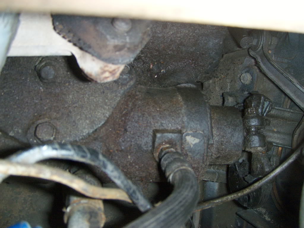 A clearer shot of the 12 point bolt on the steering box side of the rag joint (far right). The side attached to the steering shaft is already removed. Behind it is the shift arm and one of the two bolts mounting the steering shaft to the firewall.